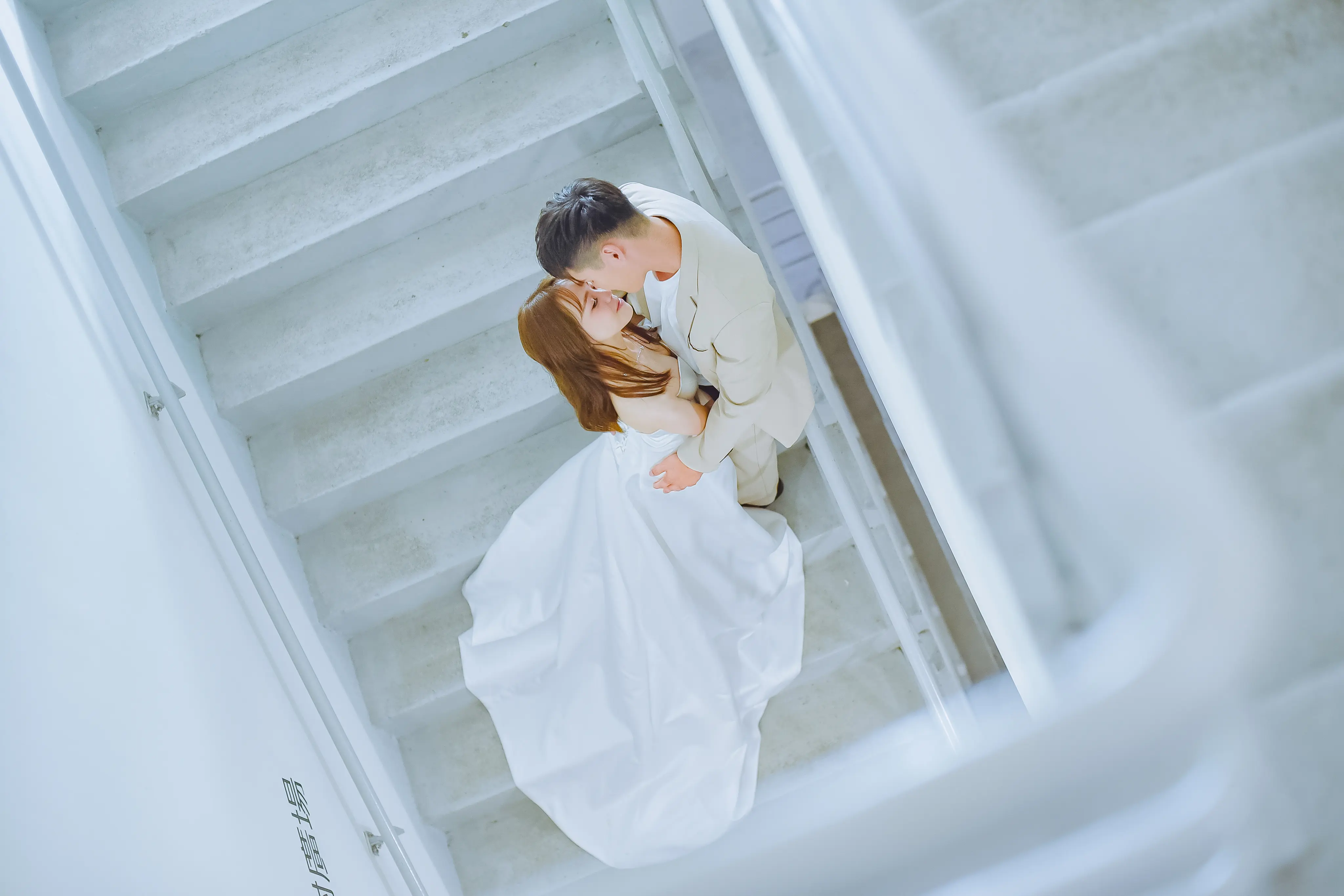 浪漫婚紗照：新人在白色建築與輕柔頭紗間親密互動