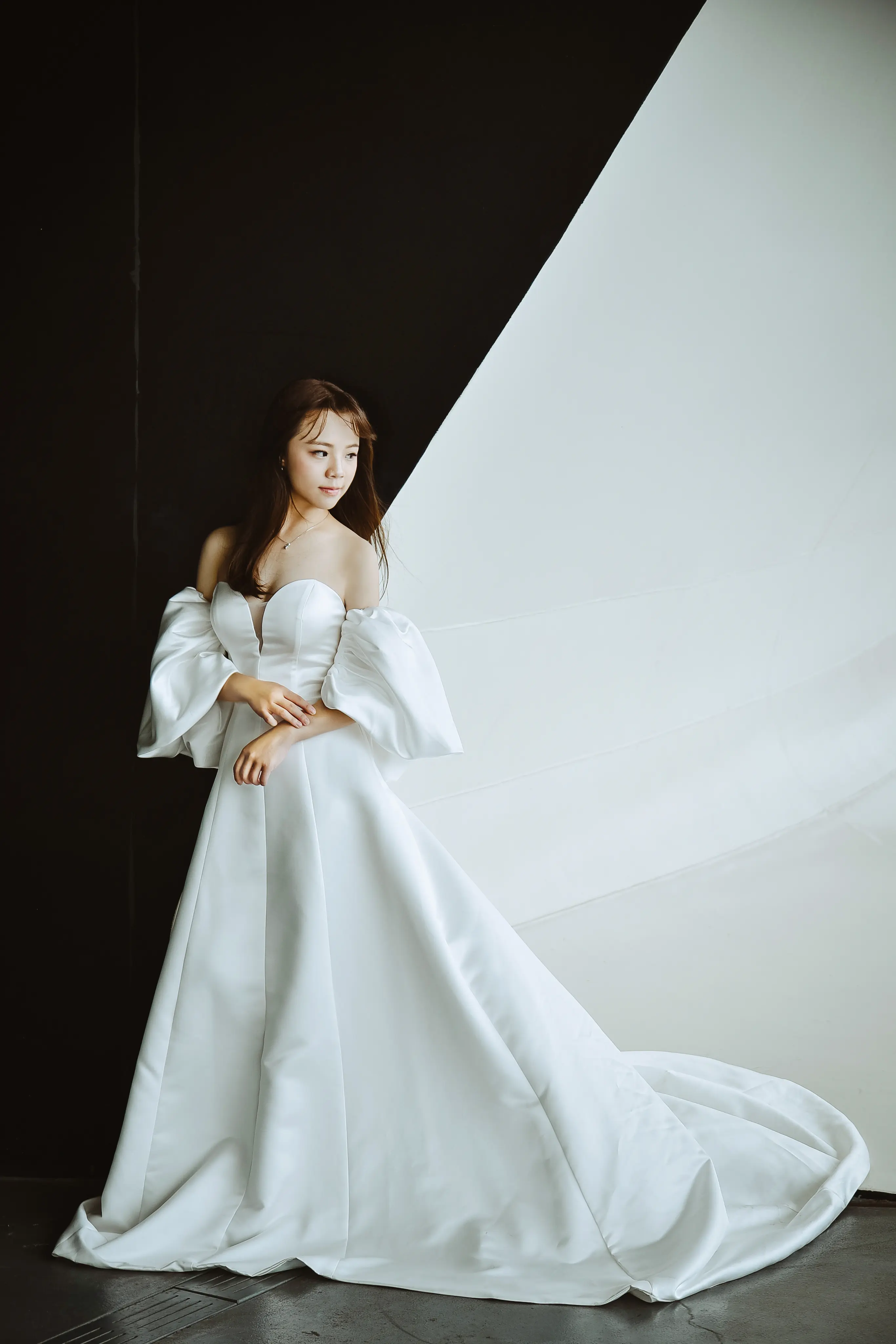 白紗藝術照：新娘穿著長拖尾婚紗站在極簡建築前