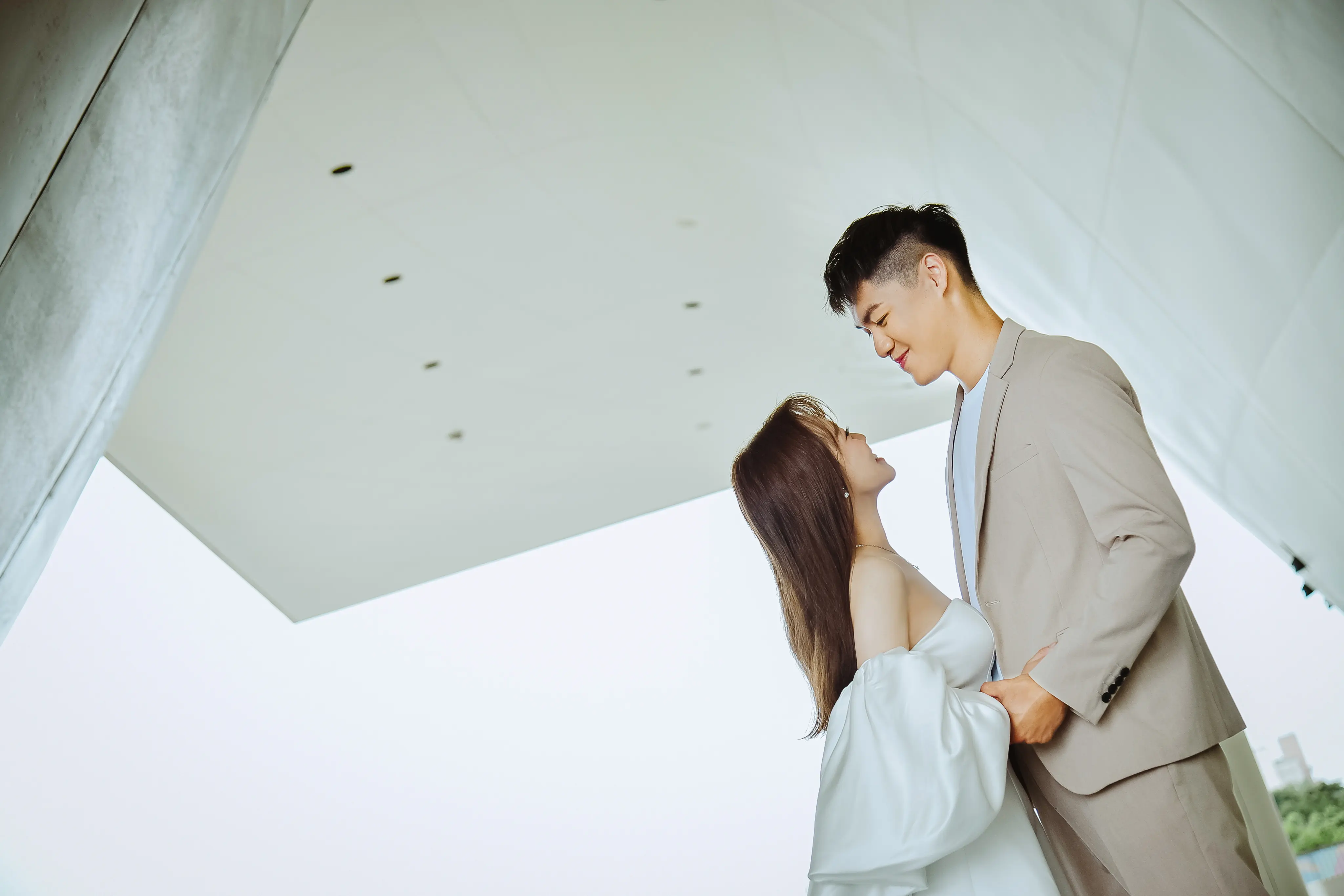 浪漫婚紗寫真：白紗新娘抬頭與淺色西裝新郎親密對望