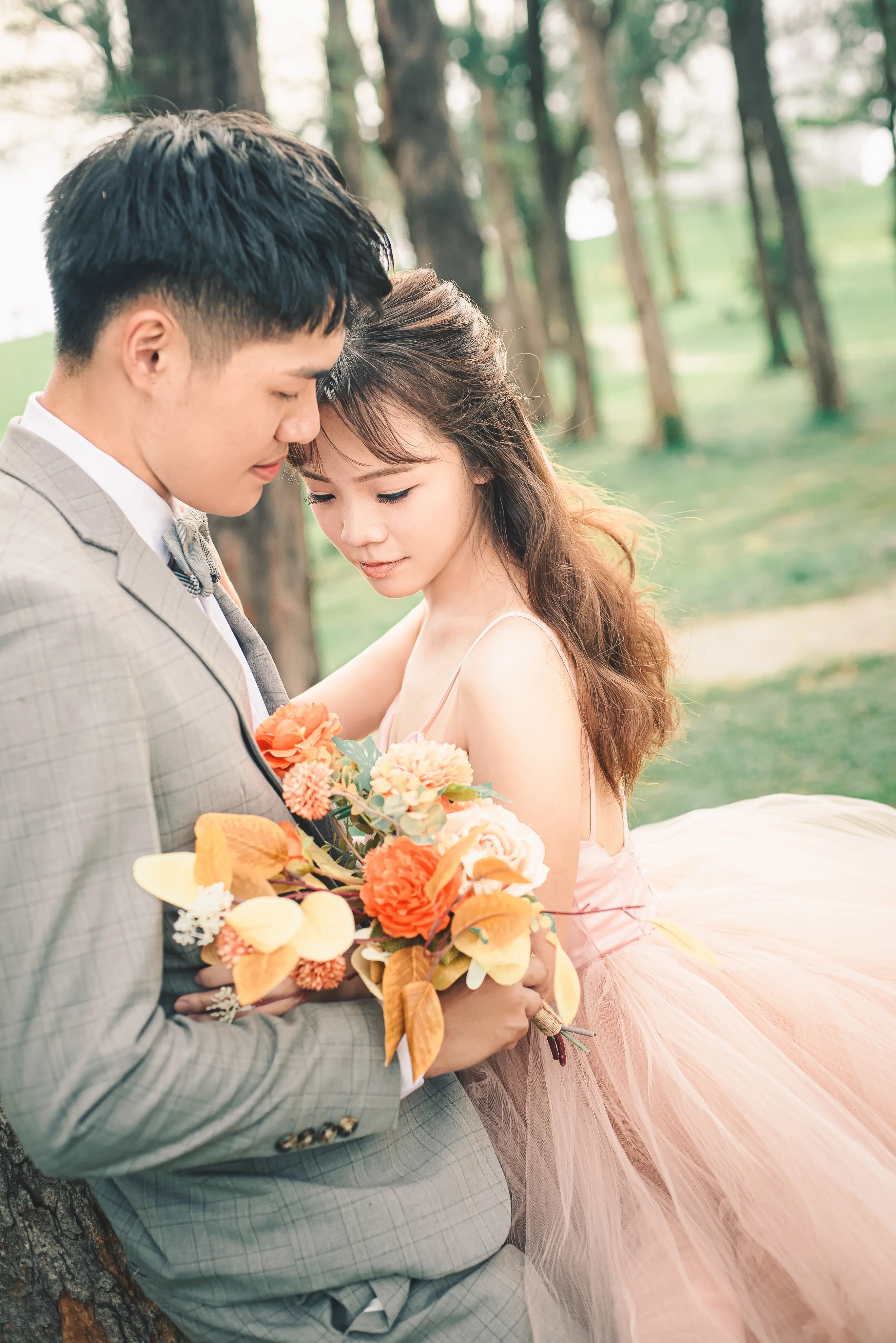 浪漫婚紗照：新人穿粉色禮服與西裝，在樹林間親密依偎