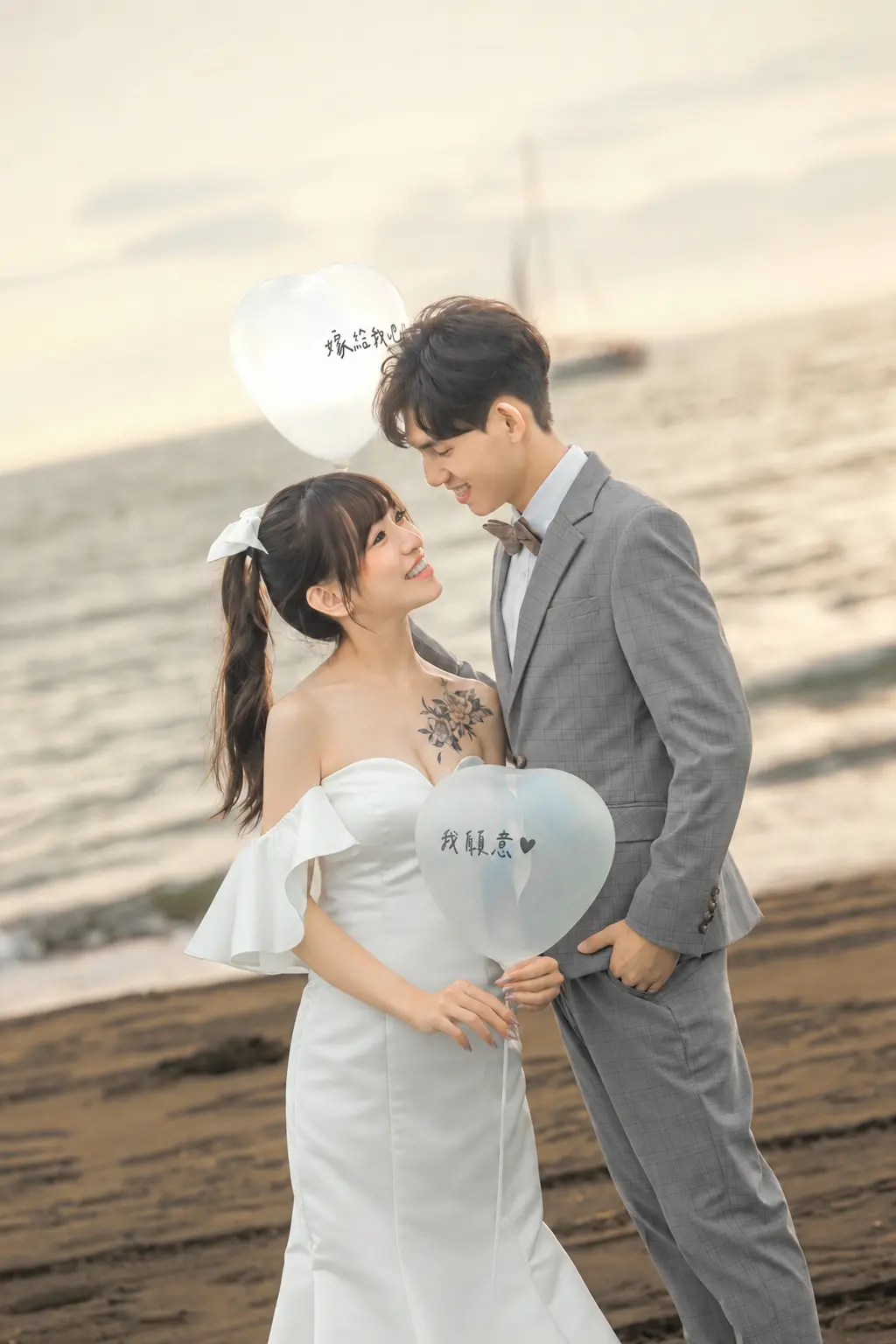 女生手持心形氣球，與穿灰色西裝的男生在海邊對望