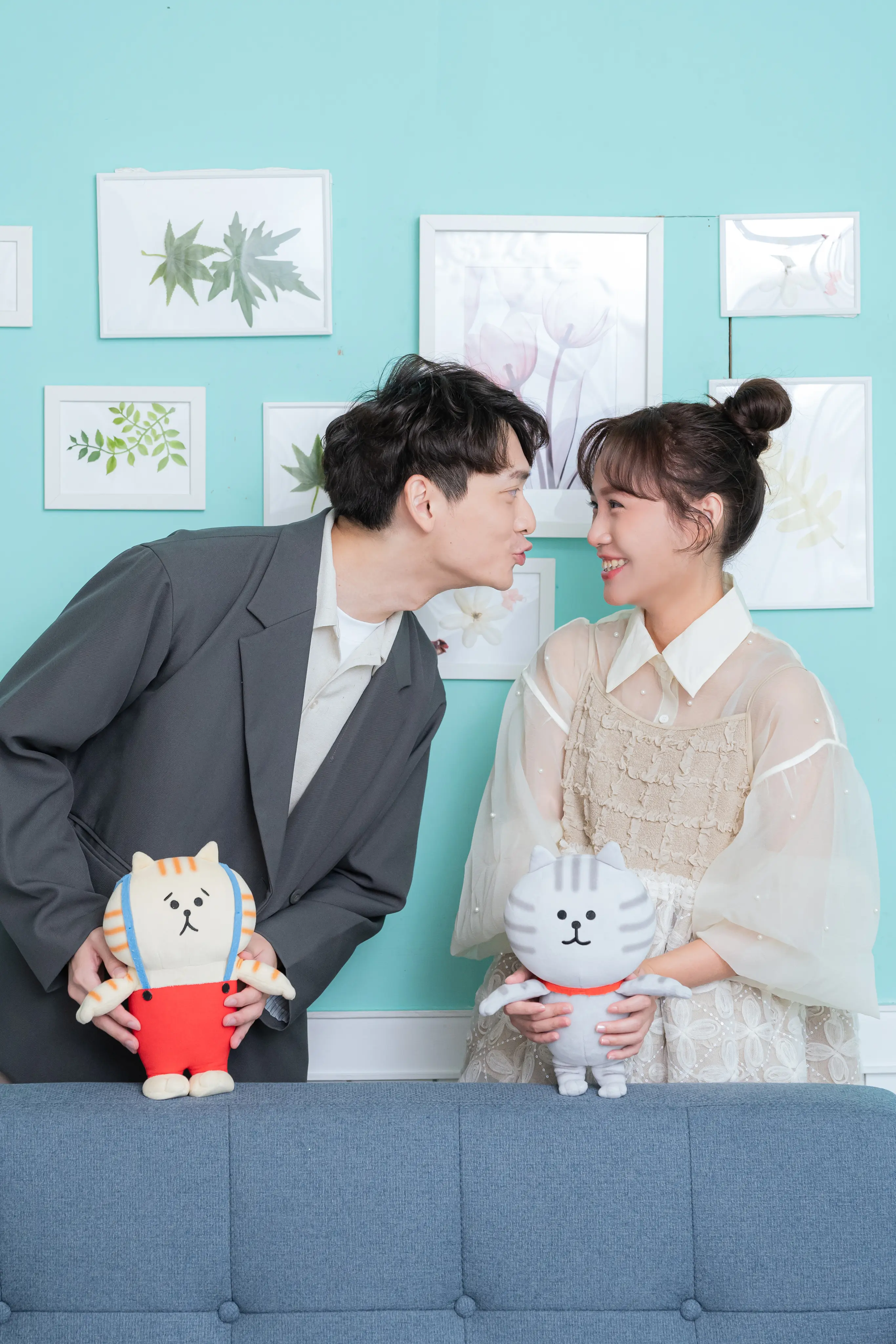 便服新人手持貓咪玩偶，男生嘟嘴靠近微笑的女生