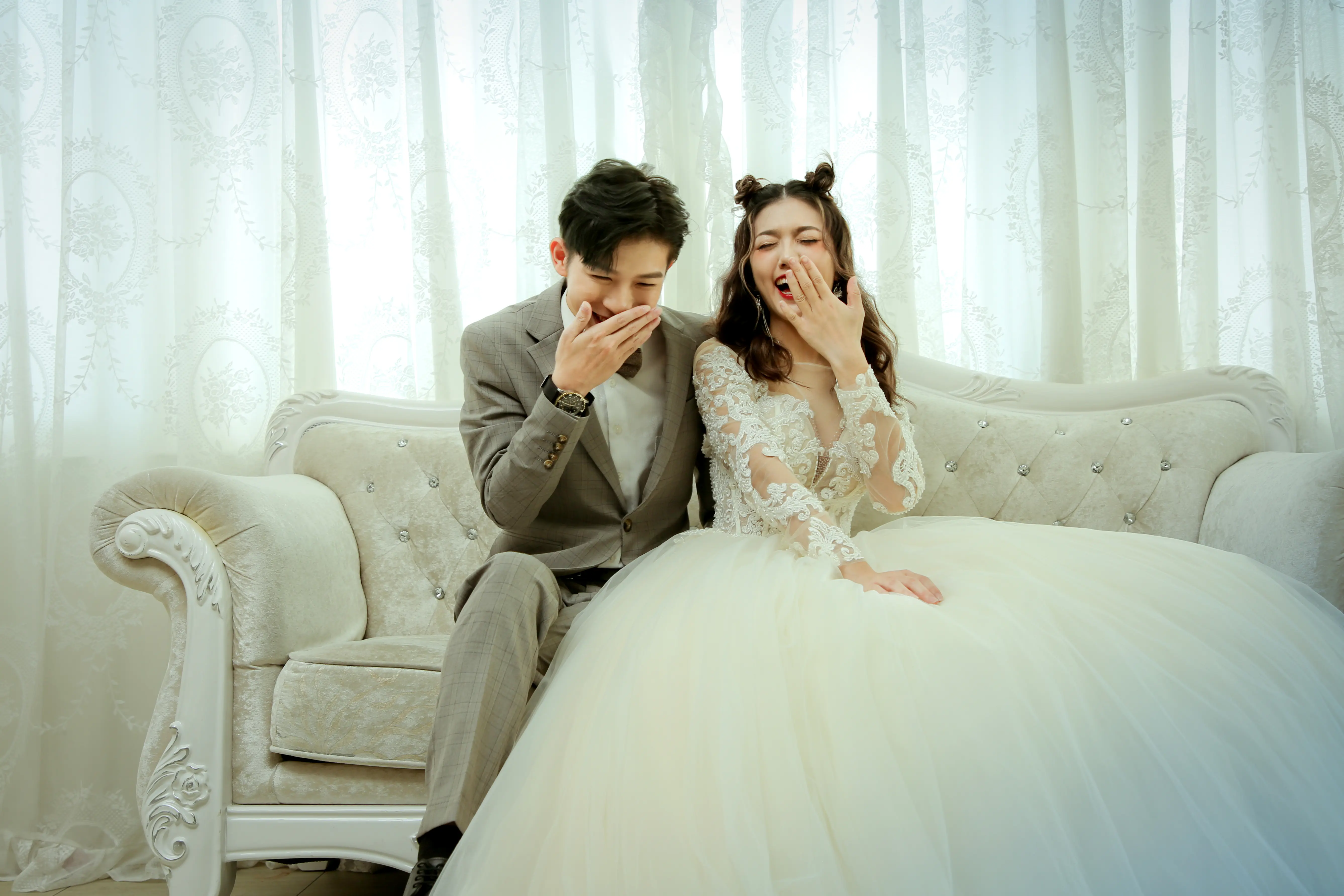 新人穿著白色婚紗與西裝坐在淺色沙發上自然互動