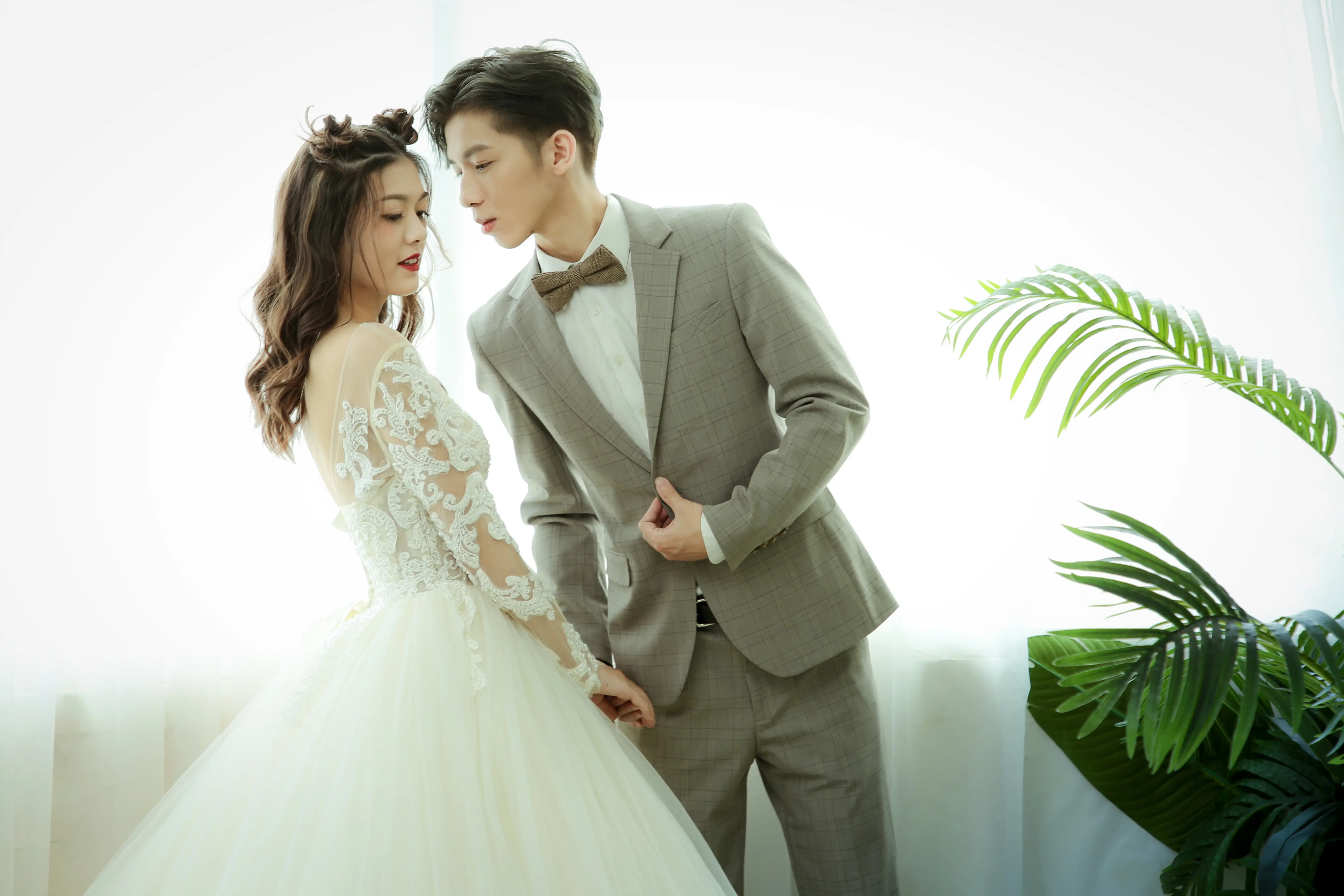 穿著白色婚紗的新娘與灰色西裝新郎在明亮室內親密互動